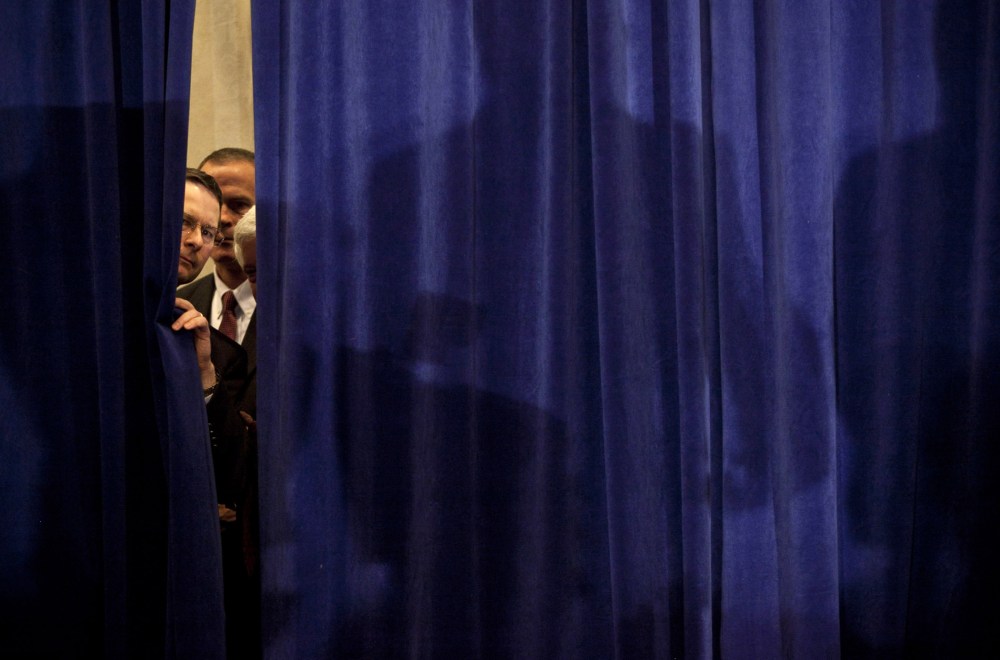 Security peeks through a curtain before Republican presidential candidate, former Speaker of the House Newt Gingrich arrived for a party on primary night January 10, 2012 in Manchester, New Hampshire.