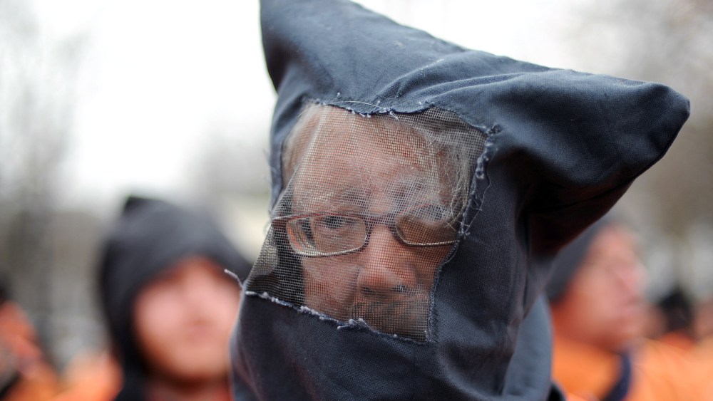 File Photo: David Barrows and fellow members of the organization Witness Against Torture wear orange prison jump suits with handcuffs and a hood over their heads during a demonstration urging the government to close down the detention facility at...
