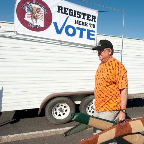 File Photo: A man carries his guns past a voter registration booth on his way to a gun show at the Arizona state fairgrounds  February 25, 2012 in Phoenix, Arizona. The Arizona and Michigan primaries are scheduled to be held February 28, 2012. (Photo...