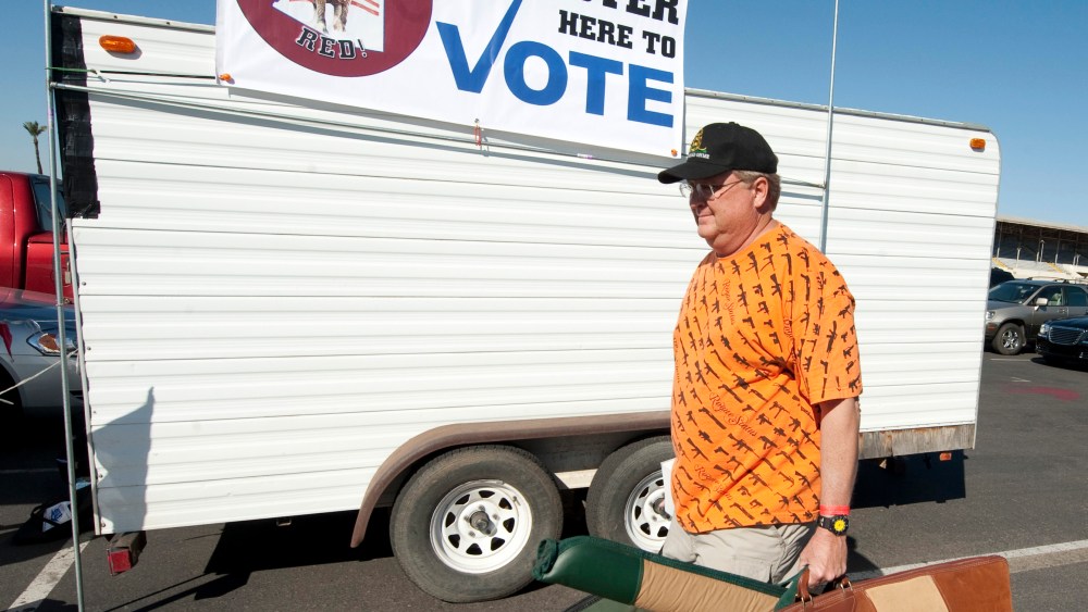File Photo: A man carries his guns past a voter registration booth on his way to a gun show at the Arizona state fairgrounds  February 25, 2012 in Phoenix, Arizona. The Arizona and Michigan primaries are scheduled to be held February 28, 2012. (Photo...