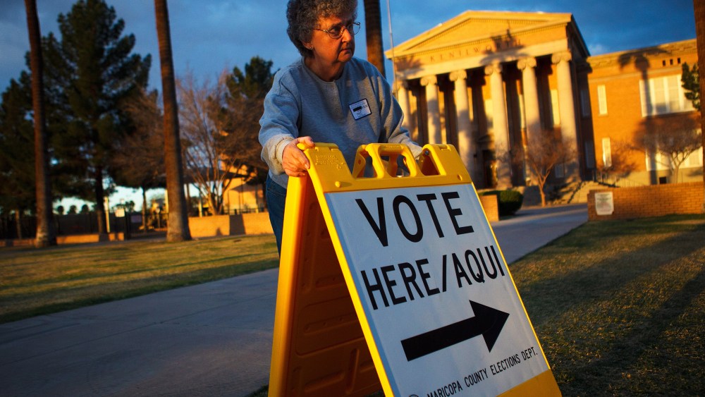 Election day volunteer Vicki Groff places a sign to direct voters to a polling station at Kenilworth School February 28, 2012 in Phoenix, Arizona.