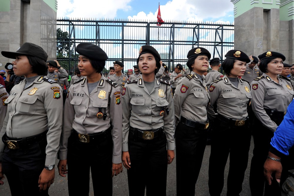 Indonesian policewomen stand guard while Indonesian workers of the All-Indonesia workers union (SPSI) hold a protest against the government's plan to hike fuel prices in Jakarta on March 29, 2012.