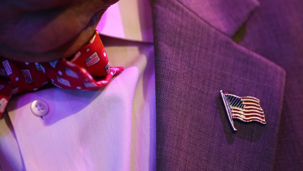 A man wears an American flag bowtie and lapel pin.
