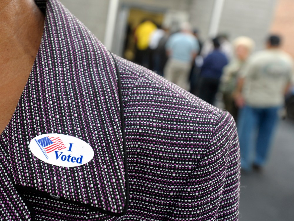 File Photo: A voter displays their "I Voted" sticker on their lapel after voting as others wait in line for the first day of Early Voting on October 18, 2012 in Wilson, North Carolina. Early Voting is offered at select location from now through...