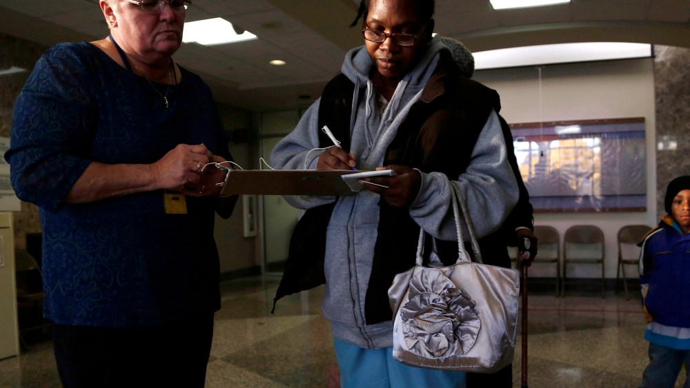 Hezkie Vburgess (C) shows proof of residency to a poll worker during early voting at the Milwaukee Municipal Building on Oct. 22, 2012 in Milwaukee, Wis.