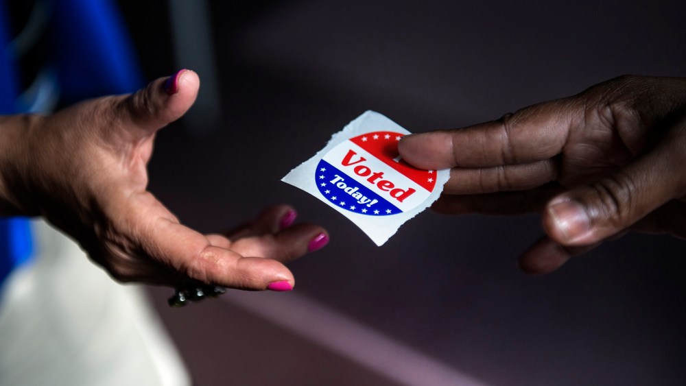 A poll worker hands out "I Voted Today" stickers on October 22, 2012