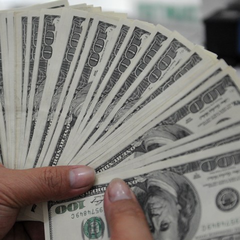 An employee at a money changer counts $100 bills.