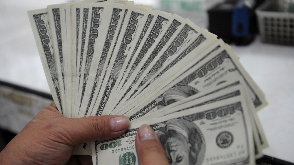 An employee at a money changer counts $100 bills.