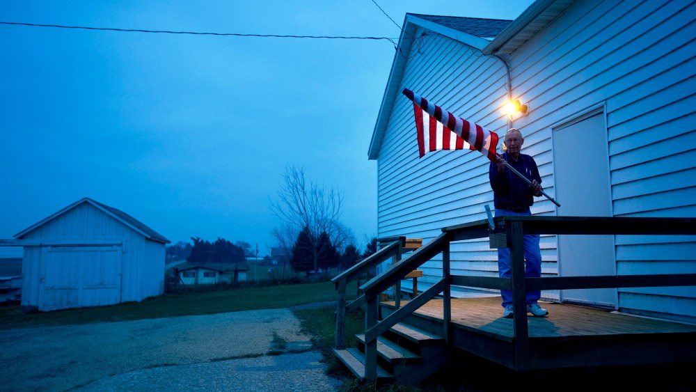 Election Inspector Jim Nodorft unfurls the American flag to hang it up outside the Smelser Town hall as the polls opened at 7 a.m. on November 6, 2012 in Georgetown, Wisconsin.
