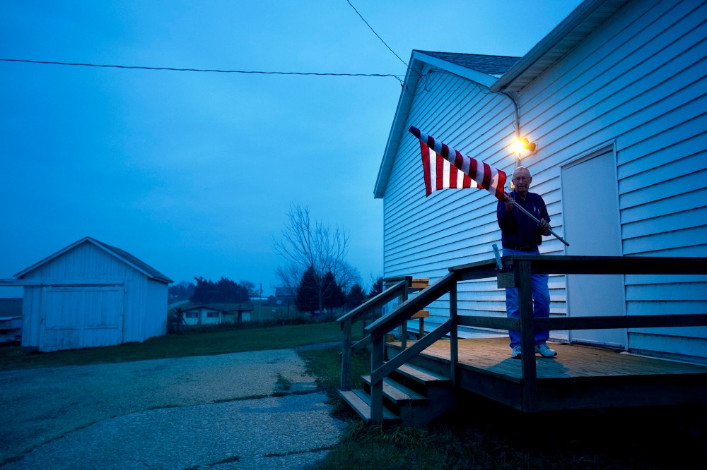 Election Inspector Jim Nodorft unfurls the American flag to hang it up outside the Smelser Town hall as the polls opened at 7 a.m. on November 6, 2012 in Georgetown, Wisconsin.