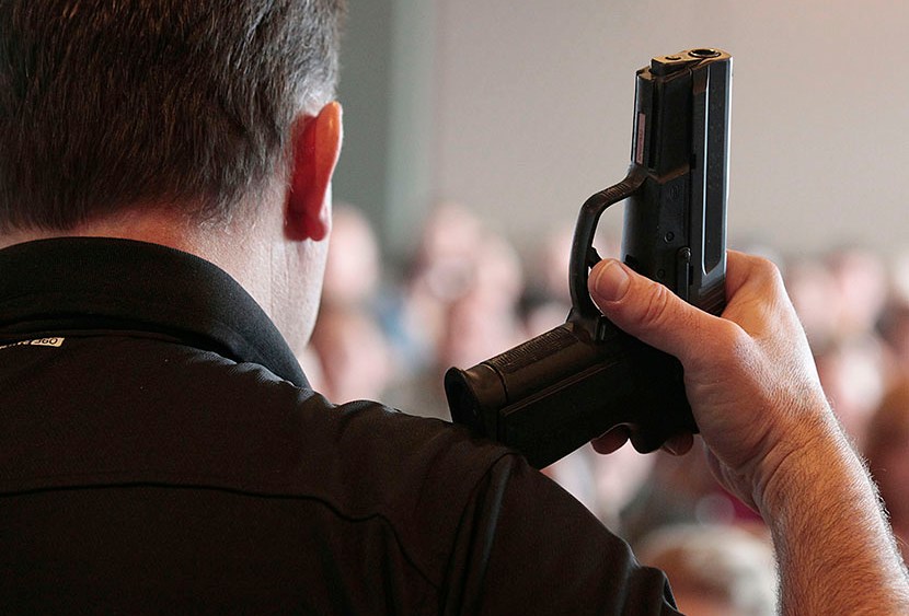 A firearm instructor holds a handgun up as he teaches a concealed-weapons training class to teachers in West Valley City, Utah.