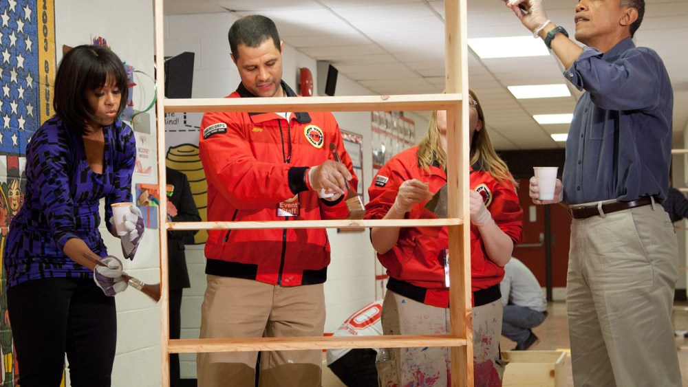 President Barack Obama (R) and first lady Michelle Obama (L) help Jeff Franco (2L), Executive Director of City Year, and Sheri Fisher, a City Year employee, to stain a bookshelf at Burrville Elementary School January 19, 2013 in Washington, DC. The...