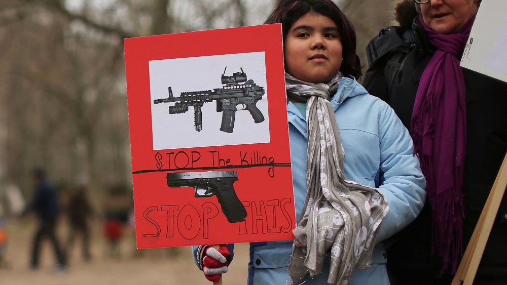 Luna Miller holds a anti gun sign while participating in a rally and march across the Brooklyn Bridge with One Million Moms for Gun Control, a gun control group formed in the wake of last month's massacre at a Newtown, Connecticut elementary school on...