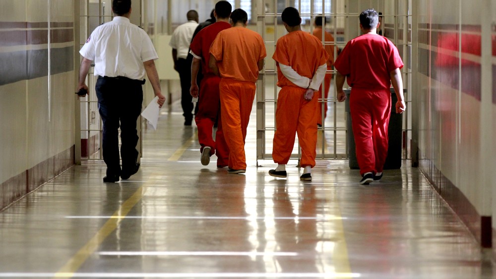 Detainees at the Stewart Detention Center in Lumpkin, Ga. are escorted through a corridor. (Photo by Jonathan Wiggs/The Boston Globe via Getty)