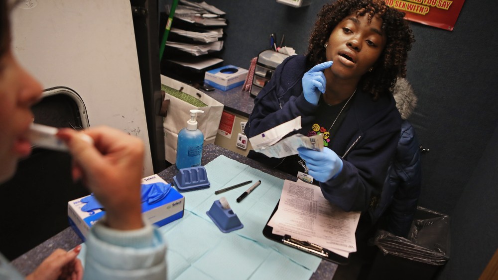 Community Health Educator Nanah Fofanah guides a young woman through an oral HIV test inside a mobile testing vehicle in Washington, DC, Feb. 7, 2013.