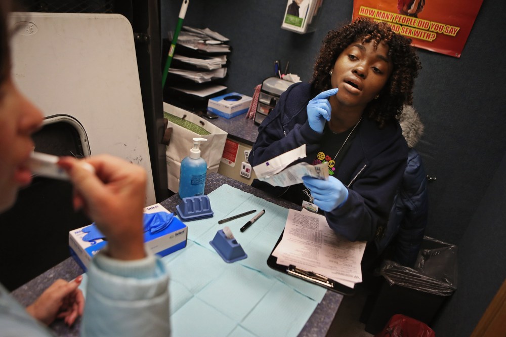 Community Health Educator Nanah Fofanah guides a young woman through an oral HIV test inside a mobile testing vehicle in Washington, DC, Feb. 7, 2013.