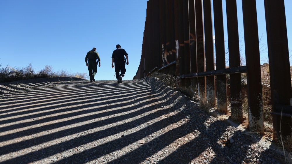 U.S. Customs and Border Protection personnel walk along a section of the recently-constructed fence at the U.S.-Mexico border on Feb. 26, 2013 in Nogales, Ariz.