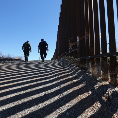 U.S. Customs and Border Protection personnel walk along a section of the recently-constructed fence at the U.S.-Mexico border on Feb. 26, 2013 in Nogales, Ariz. (Photo by John Moore/Getty)