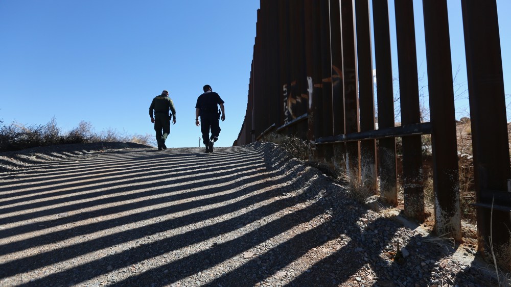 U.S. Customs and Border Protection personnel walk along a section of the recently-constructed fence at the U.S.-Mexico border on Feb. 26, 2013 in Nogales, Ariz. (Photo by John Moore/Getty)