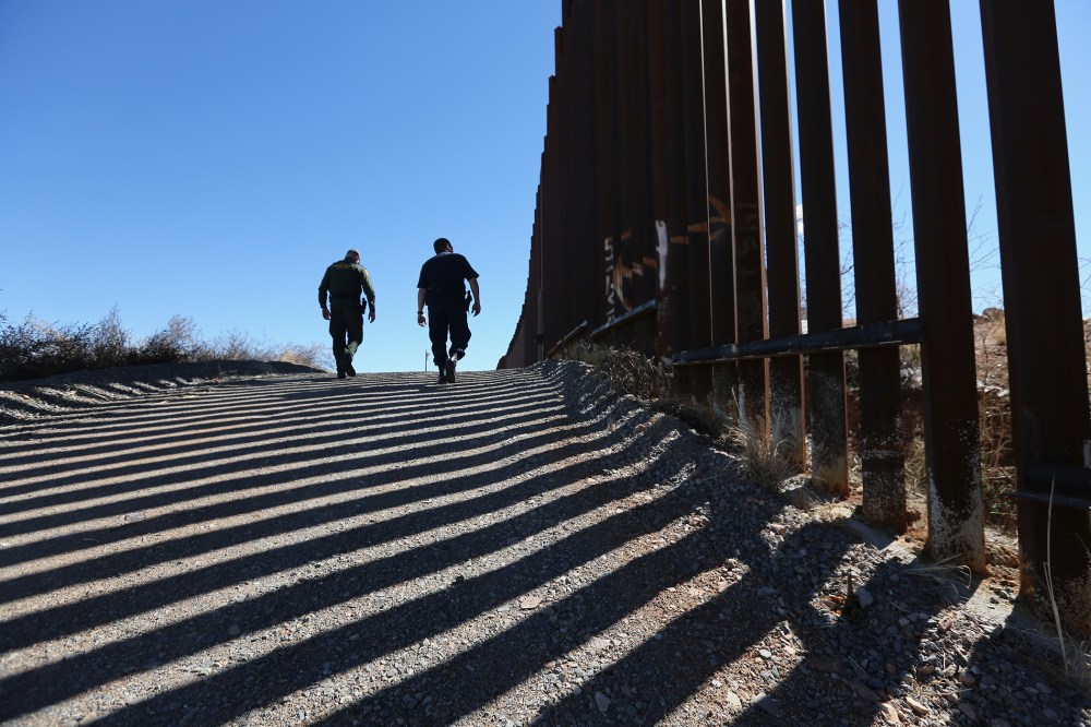 U.S. Customs and Border Protection personnel walk along a section of the recently-constructed fence at the U.S.-Mexico border on Feb. 26, 2013 in Nogales, Ariz. (Photo by John Moore/Getty)