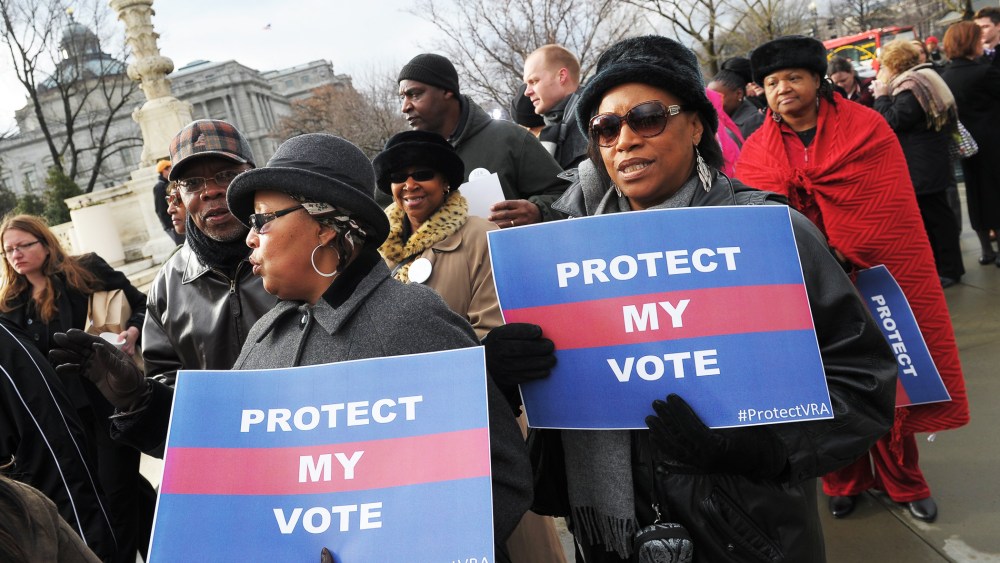 Activists hold a pro-voting rights placards outside of the US Supreme Court on February 27, 2013 in Washington, DC as the Court prepares to hear Shelby County vs Holder.