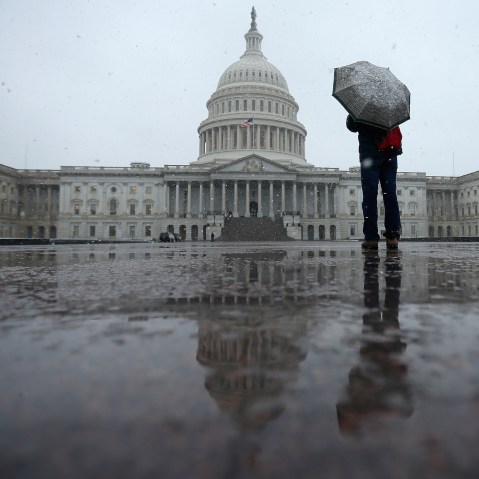 A tourist takes cover underneath an umbrella while snapping a photo of the U.S. Capitol as snow and rain falls March 6, 2013 in Washington, DC. A late winter storm is expected to cover the Mid-Atlantic region after dropping almost a foot of snow across...