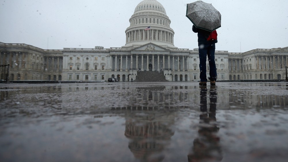 A tourist takes cover underneath an umbrella while snapping a photo of the U.S. Capitol as snow and rain falls March 6, 2013 in Washington, DC. A late winter storm is expected to cover the Mid-Atlantic region after dropping almost a foot of snow across...
