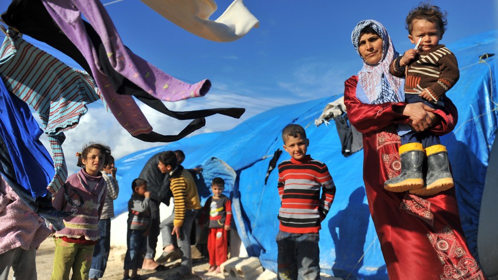 A Syrian woman carries her child outside their makeshift house at the refugee camp of Qah along the Turkish border in the village of Atme in the northwestern province of Idlib, on March 17, 2013. The conflict has killed at least 70,000 people, and...