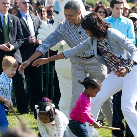 President Barack Obama  and Michelle Obama (R) cheer on children as they race to roll eggs as they participate in the White House Easter Egg Roll April 1, 2013. (Photo by Saul Loeb/AFP/Getty Images)
