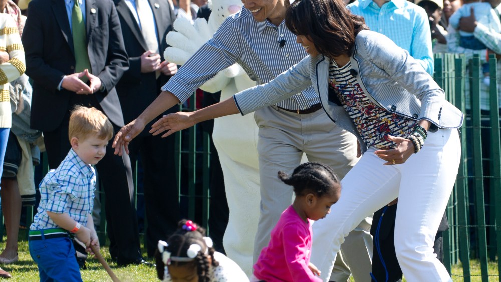 President Barack Obama  and Michelle Obama (R) cheer on children as they race to roll eggs as they participate in the White House Easter Egg Roll April 1, 2013. (Photo by Saul Loeb/AFP/Getty Images)