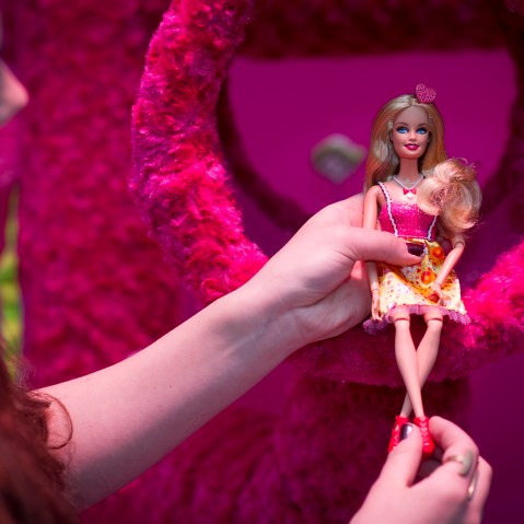 A woman holds a Barbie doll at 'Barbie: The Dreamhouse Experience'  in Berli, April 12, 2013.