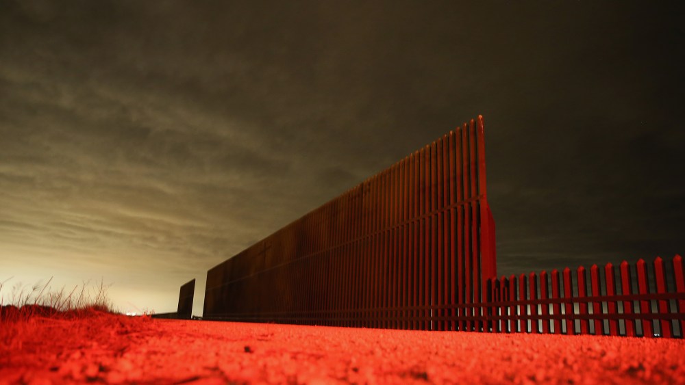 Lit by the tail light of a U.S. Border Patrol vehicle, a section of the U.S.- Mexico border fence stands on April 10, 2013 in La Joya, Texas.