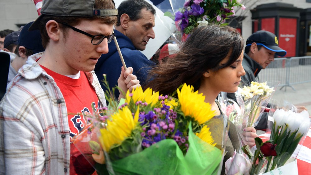 After the barricades were moved up along Boylston street to the corner with Berkeley people walk along holding flags and memorials following yesterday's bomb attack on the Boston Marathon April 16, 2013 in Boston, Massachusetts. Security is tight in...