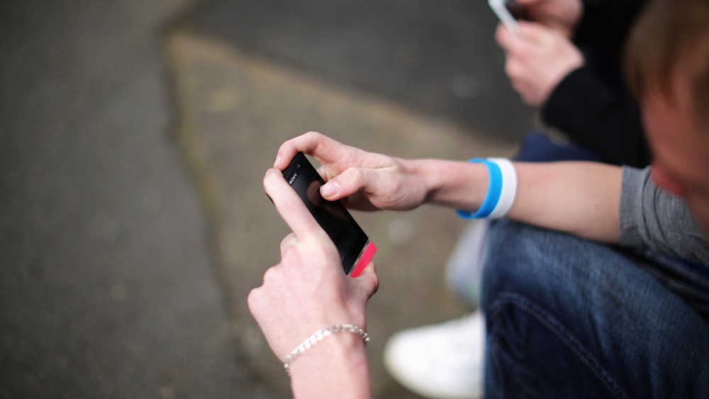 Two youths send text messages on their smart phones. (Photo by Christopher Furlong/Getty)
