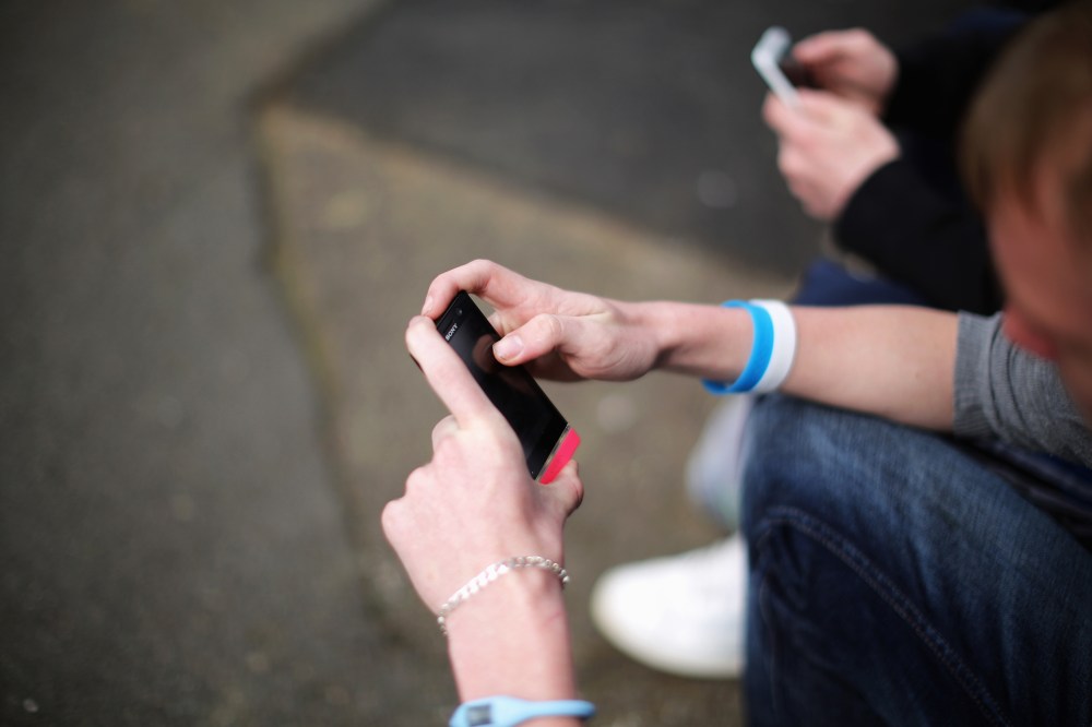 Two youths send text messages on their smart phones. (Photo by Christopher Furlong/Getty)