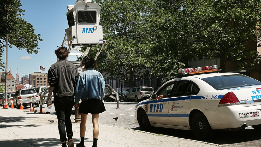 A couple walk past a police observation pod in a neighborhood with heavy crime on June 4, 2013 in the Brooklyn borough of New York City.