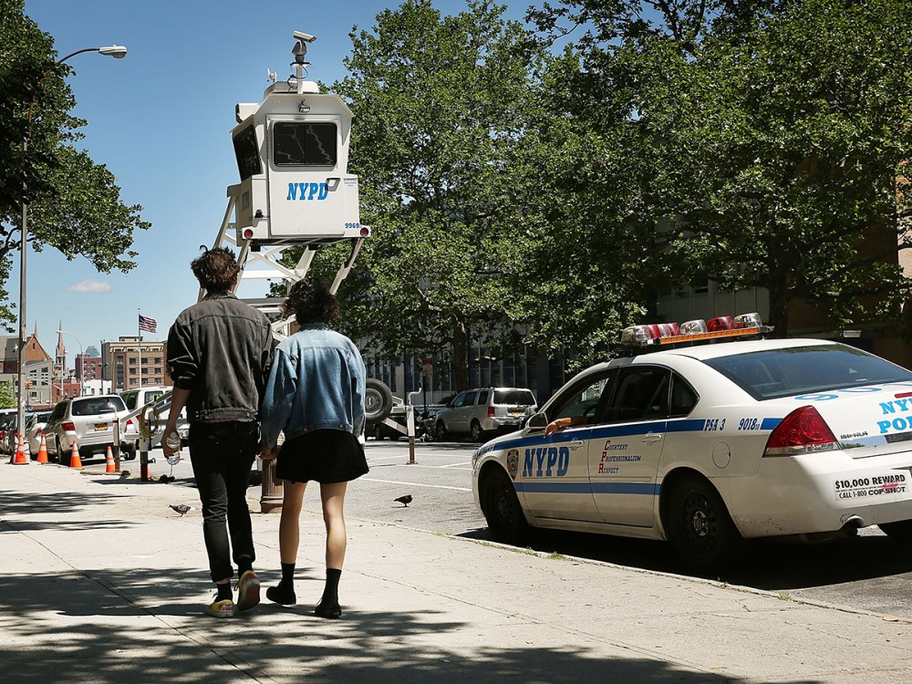 A couple walk past a police observation pod in a neighborhood with heavy crime on June 4, 2013 in the Brooklyn borough of New York City.
