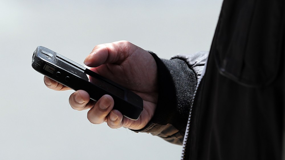 A pedestrian uses a smartphone as he walks along Market Street on June 5, 2013 in San Francisco, California.