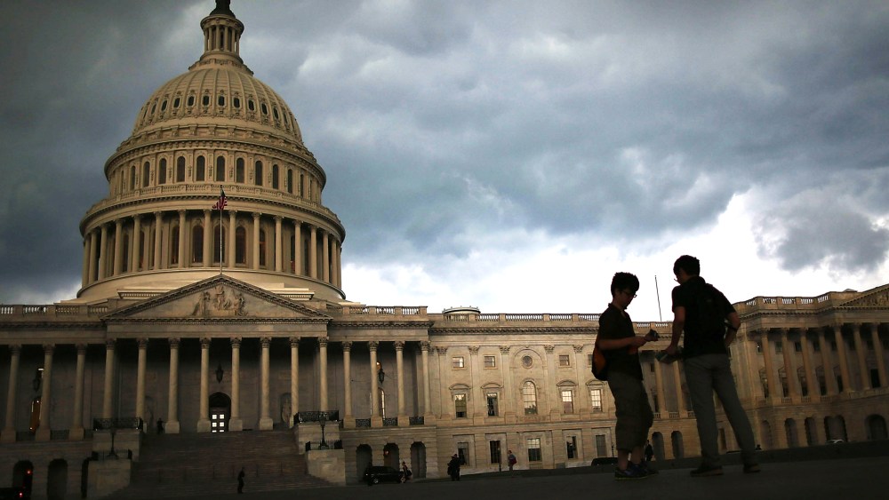 Two men stand on the plaza of the U.S. Capitol Building as storm clouds fill the sky, June 13, 2013 in Washington, DC.