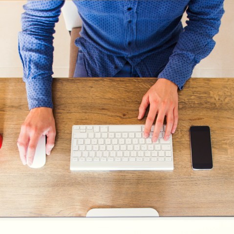 Image: A man uses a computer on a tidy desk
