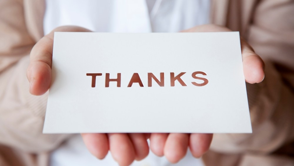 Image: A woman holds a thank you card