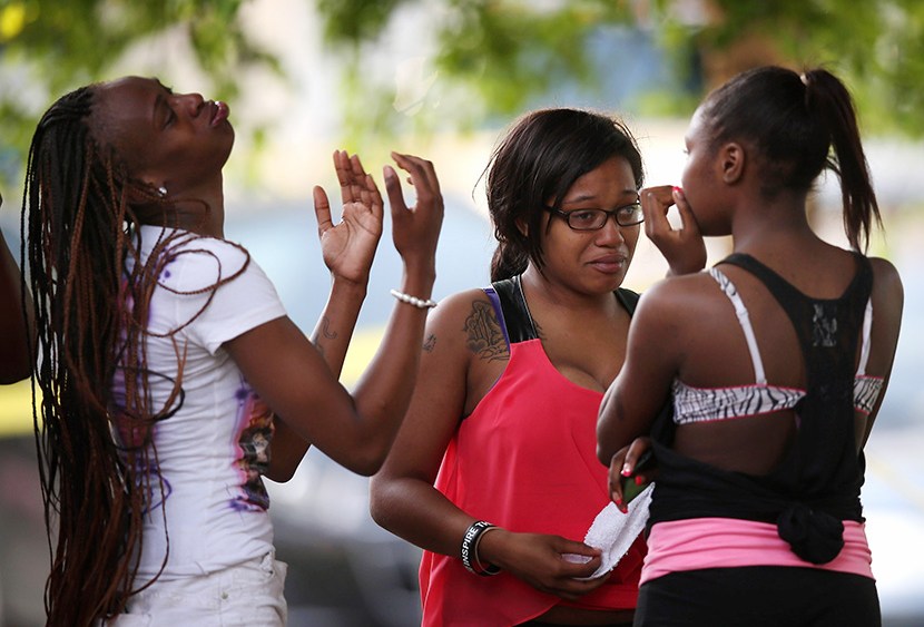 Young women watch as police prepare to remove the remains of their friend after he was shot and killed on June 22, 2013 in Chicago, Illinois. (Photo by Scott Olson/Getty Images)