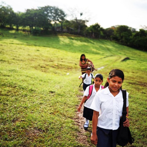 Girls walk to school accompanied by their mother, in the village of Metalio, El Salvador, July 1, 2013.