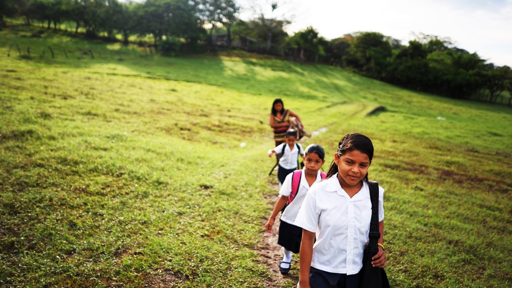 Girls walk to school accompanied by their mother, in the village of Metalio, El Salvador, July 1, 2013.