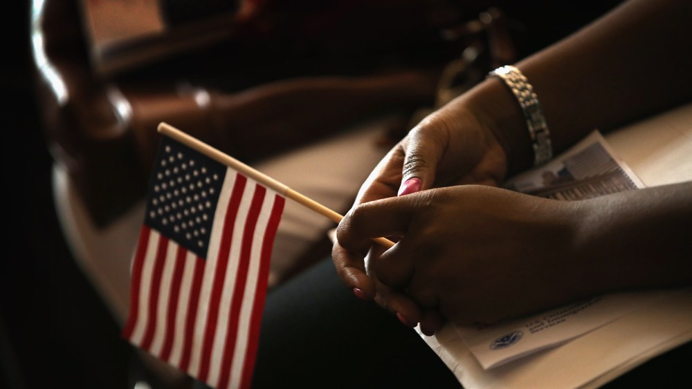 A new U.S. citizen holds an American flag along with her citizenship papers as she participates in a naturalization ceremony at the Chicago Cultural Center on July 3, 2013 in Chicago, Ill.