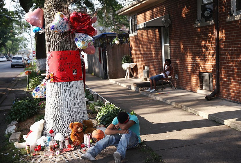 A teenage boy grieves next to a makeshift memorial at the site where Ashley Hardmon was shot and killed on July 4, 2013 in Chicago, Illinois. Hardmon, 19, was killed after being struck in the head by a bullet when two men opened fire on her and a group...