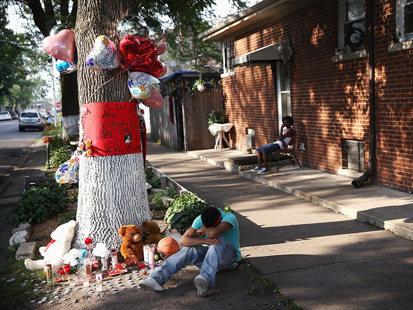 A teenage boy grieves next to a makeshift memorial at the site where Ashley Hardmon was shot and killed on July 4, 2013 in Chicago, Illinois. Hardmon, 19, was killed after being struck in the head by a bullet when two men opened fire on her and a group...