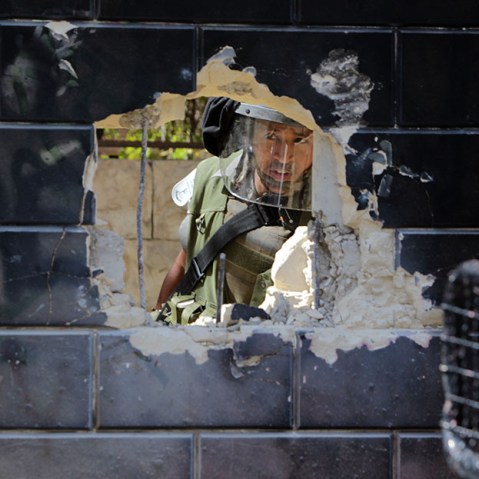 An Israeli security guard peers at a hole knocked through part of  a wall connected to Israel's controversial separation barrier by Palestinian youth in the Abu Dis neighborhood, bordering Jerusalem on July 9, 2013.  (Photo by Abbas Momani/AFP/Getty)