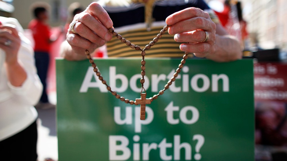 A protester holds rosary beads with a anti-abortion placard. (Photo by Peter Muhly/AFP/Getty)