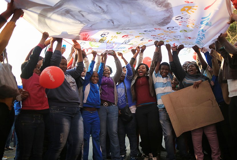 People dance and celebrate as they wave a banner of Nelson Mandela to celebrate his 95th birthday outside the Mediclinic Heart Hospital where he is being treated on July 18, 2013 in Pretoria, South Africa.   (Photo by Christopher Furlong/Getty Images)